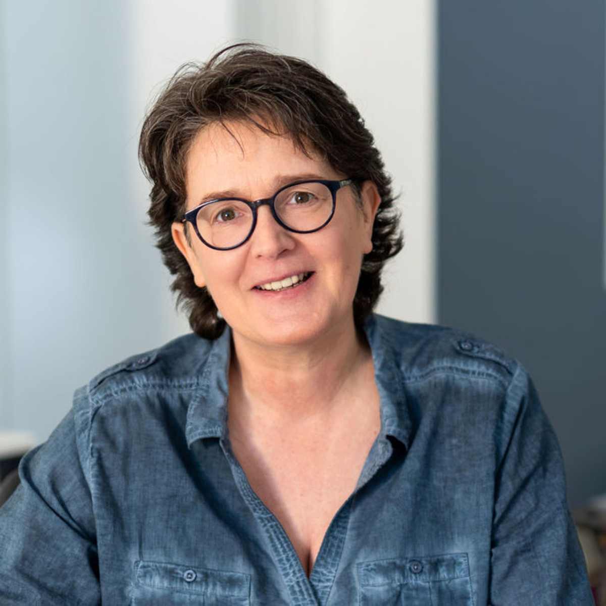 Ein einladendes Portrait von Marina Heckhoff. Mit einer offenen, präsenten Haltung steht sie im Fokus des Bildes, während der helle, unscharfe Hintergrund für eine luftige, leichte Atmosphäre sorgt – perfekt passend zu ihrer Philosophie von Mentalmentoring und nachhaltiger Gesunderhaltung.
